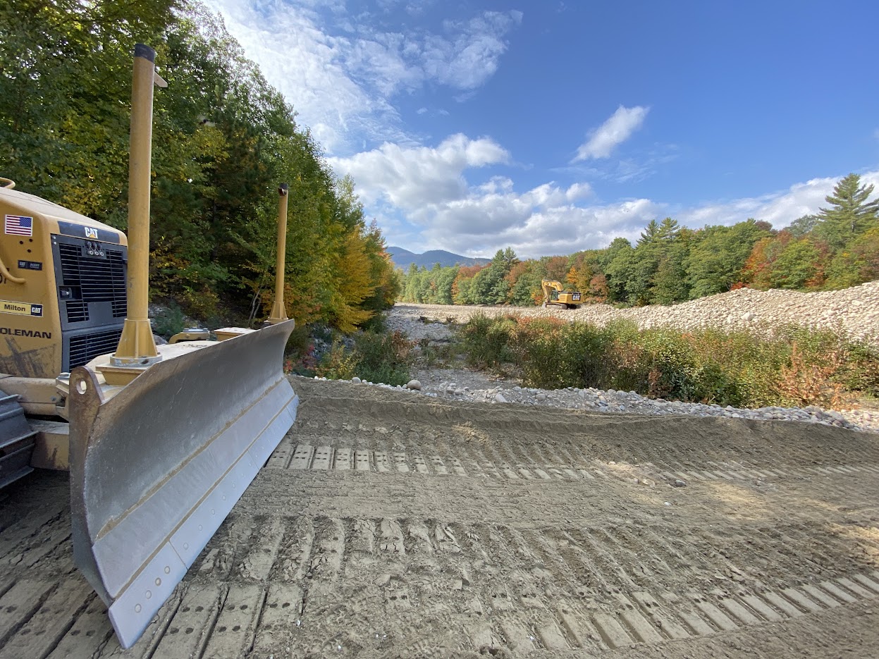 CAT bulldozer on an active stream restoration corridor with NH White Mountains and fall foliage in the background