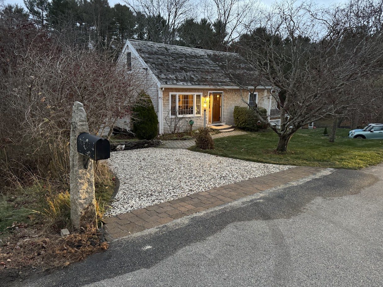 Cape-style home with a finished white gravel driveway, cobble border, and granite-post mailbox, GSS New Hampshire
