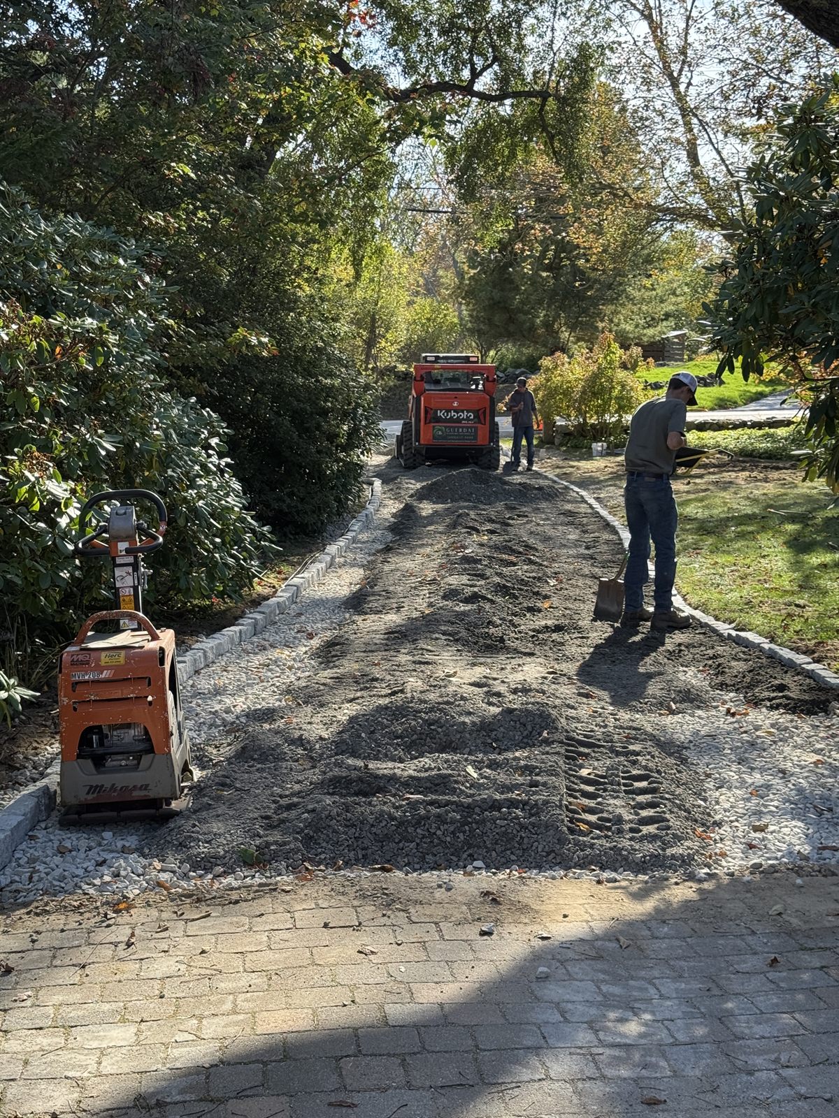 Plate compactor compacting a gravel driveway surface — GSS build process