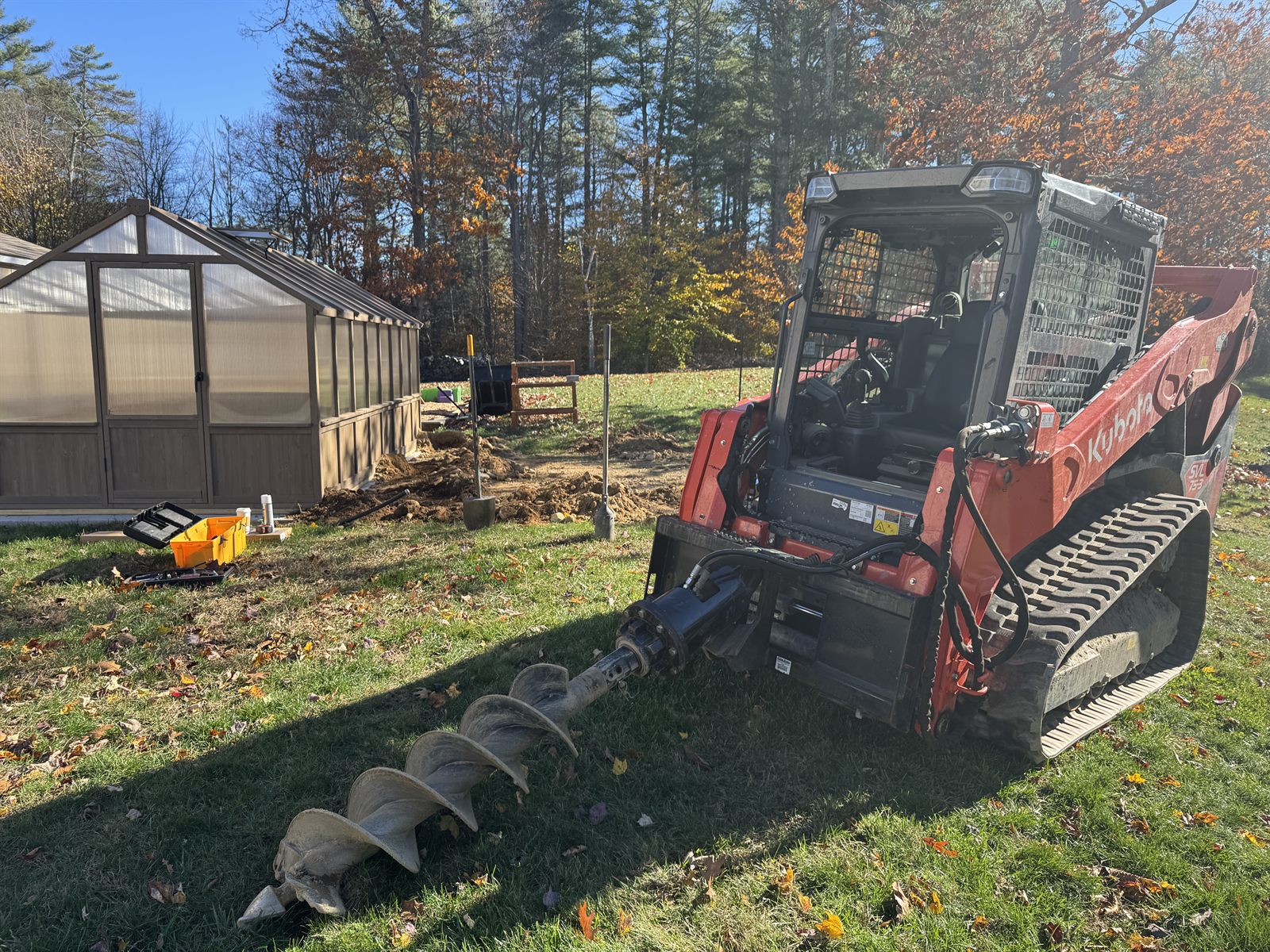 Skid steer augering fence posts beside a new greenhouse — GSS build process