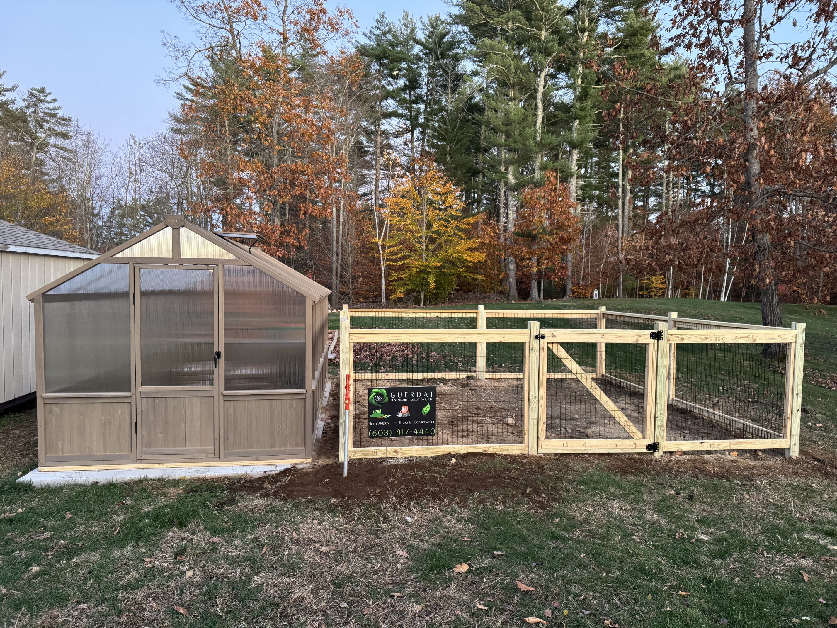 Greenhouse with attached fenced run and GSS company sign — homestead project, New Hampshire